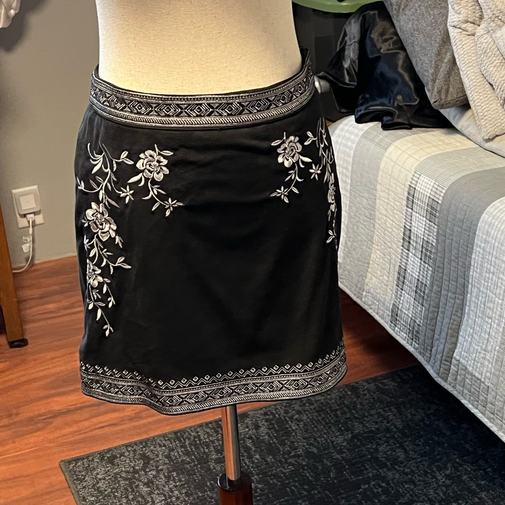 Black skirt. Embroidered at the waistband hips and along the bottom. Side zip.